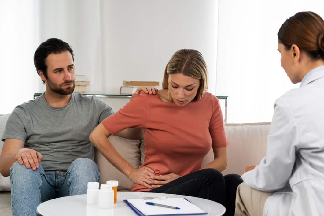 Woman experiencing abdominal pain during medical consultation with doctor.